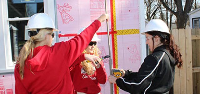group of three help at a Habitat for Humanity home construction site