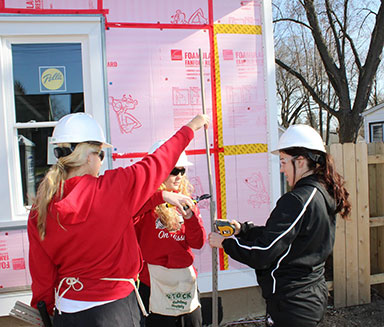 group of three help at a Habitat for Humanity home construction site
