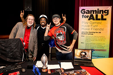 group of three poses at a student fair booth
